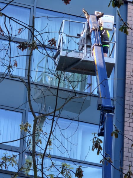 Fensterreinigung an einem Bürogebäude mit Hubsteiger und Arbeitsbühne